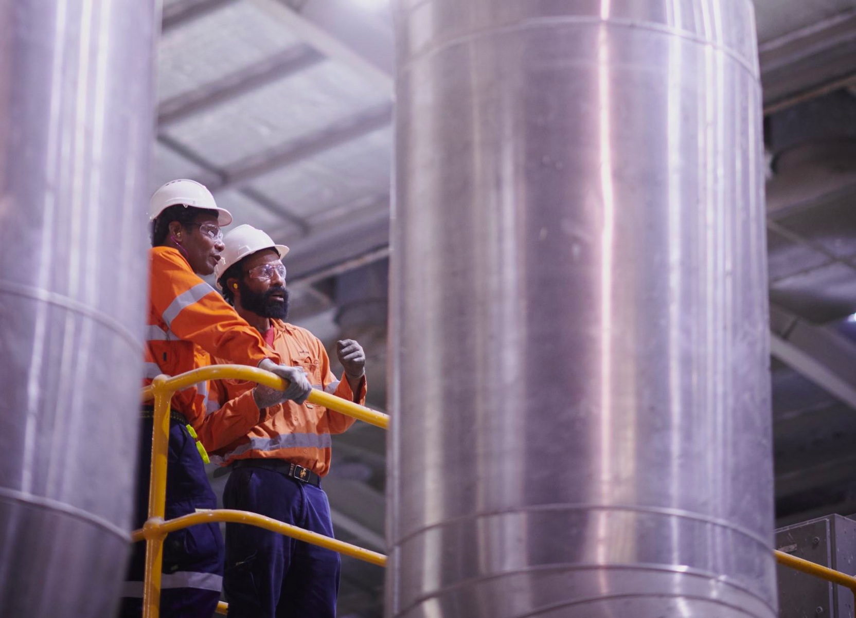 Workers talking by machinery